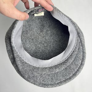 Pode incluir: Um bon&eacute; Kangol de l&atilde; cinza, visto por dentro. O bon&eacute; tem uma coroa estruturada e arredondada e uma aba r&iacute;gida. O interior apresenta uma faixa branca e uma etiqueta com o logotipo Kangol e a palavra "MEDIUM".