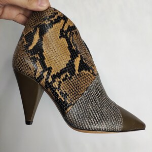 May include: Brown and black snakeskin ankle boots with a pointed toe and a green heel.