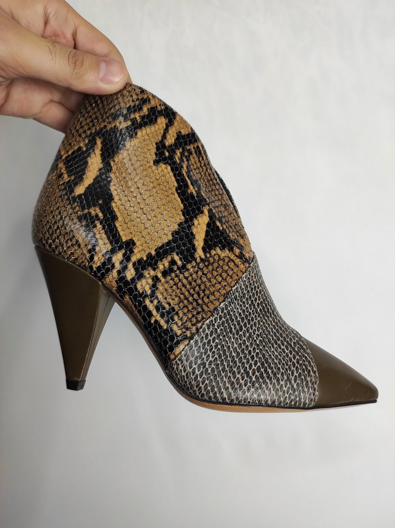 May include: Brown and black snakeskin ankle boots with a pointed toe and a green heel.