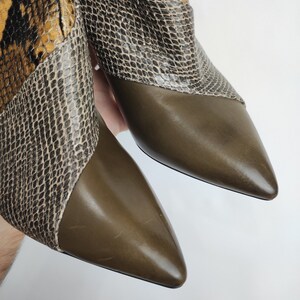 May include: A pair of brown leather ankle boots with a snakeskin pattern on the upper part of the boot. The boots have a pointed toe and a low heel.
