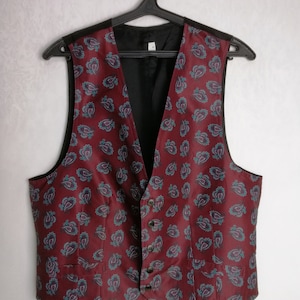 May include: A burgundy paisley patterned vest with a black lining and five buttons.