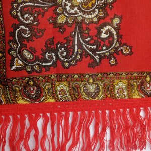 K&ouml;nnte beinhalten: Roter Schal mit Paisley-Muster und Fransenbord&uuml;re. Der Schal hat ein florales Design mit braunen, gelben und wei&szlig;en Akzenten.