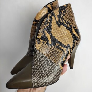 May include: A pair of brown and black snakeskin heeled ankle boots with a pointed toe.