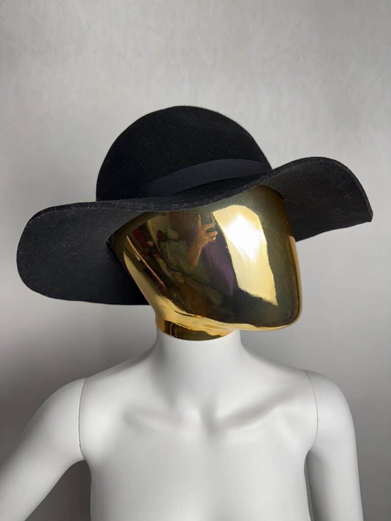 Puede incluir: Un sombrero de fieltro negro de ala ancha con una cinta negra alrededor de la corona.