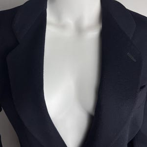 Pode incluir: Um blazer azul escuro com uma gola em V profunda e um fecho de um &uacute;nico bot&atilde;o.