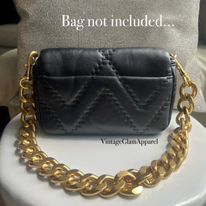 May include: A black quilted leather handbag with a thick gold chain strap. The bag has a flap closure and a small pocket on the back. The text "VintageGlamApparel" is printed on the bottom of the image.