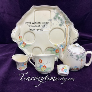 Könnte beinhalten: Unvollständiges Royal Winton Frühstücks-Set aus den 1930er Jahren. Das Set umfasst ein großes Serviertablett, eine Teekanne, einen Sahnekännchen, eine Tasse und eine kleine Tasse. Die Teile sind cremefarben mit Blumen- und Baumdesigns.