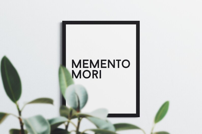 May include: A black framed print with the text "MEMENTO MORI" in white letters on a white background.