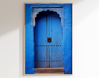 Peut inclure: Une porte en bois bleue avec une entrée cintrée et un heurtoir de porte en métal. La porte est encastrée dans un mur bleu.