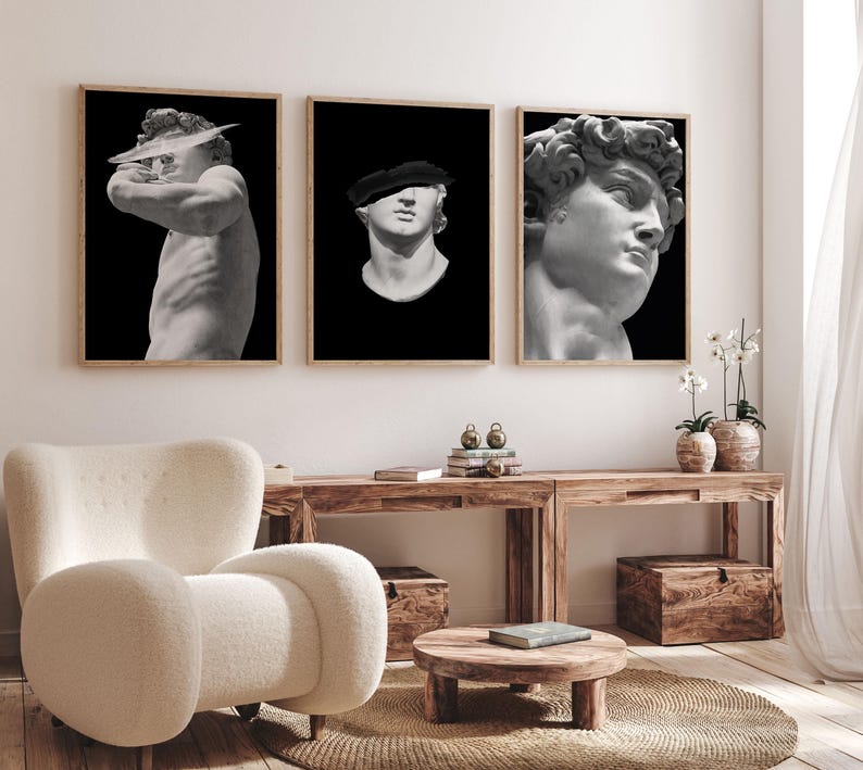 K&ouml;nnte beinhalten: Drei Schwarzwei&szlig;-Bilderrahmen mit Skulpturen. Die Bilder h&auml;ngen an einer wei&szlig;en Wand &uuml;ber einem Holztisch. Die Skulpturen zeigen einen M&auml;nnerkopf, einen M&auml;nnertorso und einen M&auml;nnerkopf mit Hut.