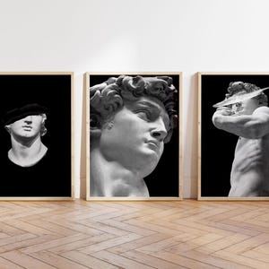 K&ouml;nnte beinhalten: Drei Schwarzwei&szlig;-Bilderrahmen mit klassischen Skulpturen. Die Skulpturen zeigen einen M&auml;nnerkopf mit Augenbinde, einen M&auml;nnerkopf mit lockigem Haar und einen M&auml;nnertorso mit einem abgebrochenen Fl&uuml;gel.