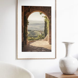 Tuscan arch print: brick Italian archway framing a countryside valley with stone path and olive trees in oil painting style.