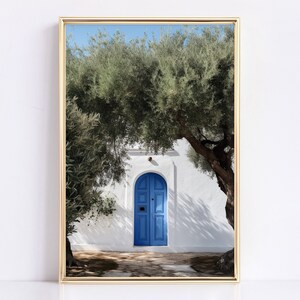 Peut inclure: Une impression encadr&eacute;e repr&eacute;sentant une porte bleue vive encastr&eacute;e dans un mur en stuc blanc, encadr&eacute;e par des oliviers verts luxuriants. L'image capture une journ&eacute;e ensoleill&eacute;e avec des ombres sur le chemin de pierre, cr&eacute;ant une esth&eacute;tique m&eacute;diterran&eacute;enne sereine.