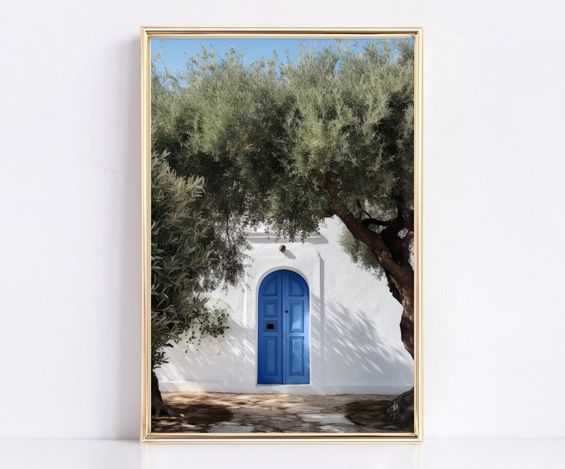 Peut inclure: Une impression encadr&eacute;e repr&eacute;sentant une porte bleue vive encastr&eacute;e dans un mur en stuc blanc, encadr&eacute;e par des oliviers verts luxuriants. L'image capture une journ&eacute;e ensoleill&eacute;e avec des ombres sur le chemin de pierre, cr&eacute;ant une esth&eacute;tique m&eacute;diterran&eacute;enne sereine.