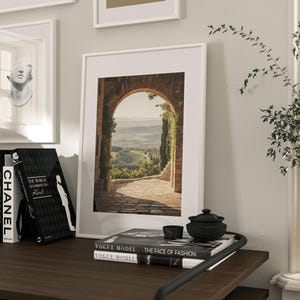 Tuscan arch print: brick Italian archway framing a countryside valley with stone path and olive trees in oil painting style.