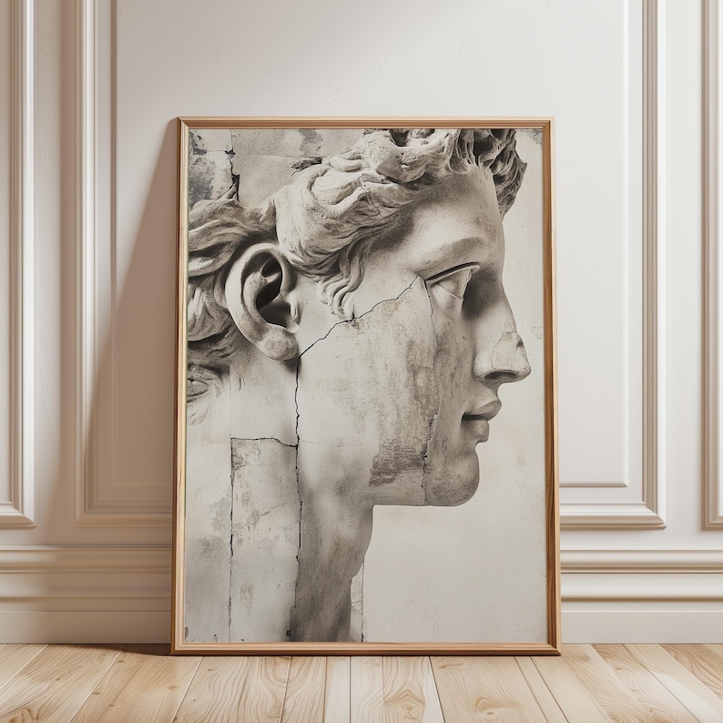 May include: A framed black and white print of a classical sculpture bust in profile. The artwork depicts a male figure with detailed facial features and curly hair, with visible cracks in the stone. The print is in a wooden frame.