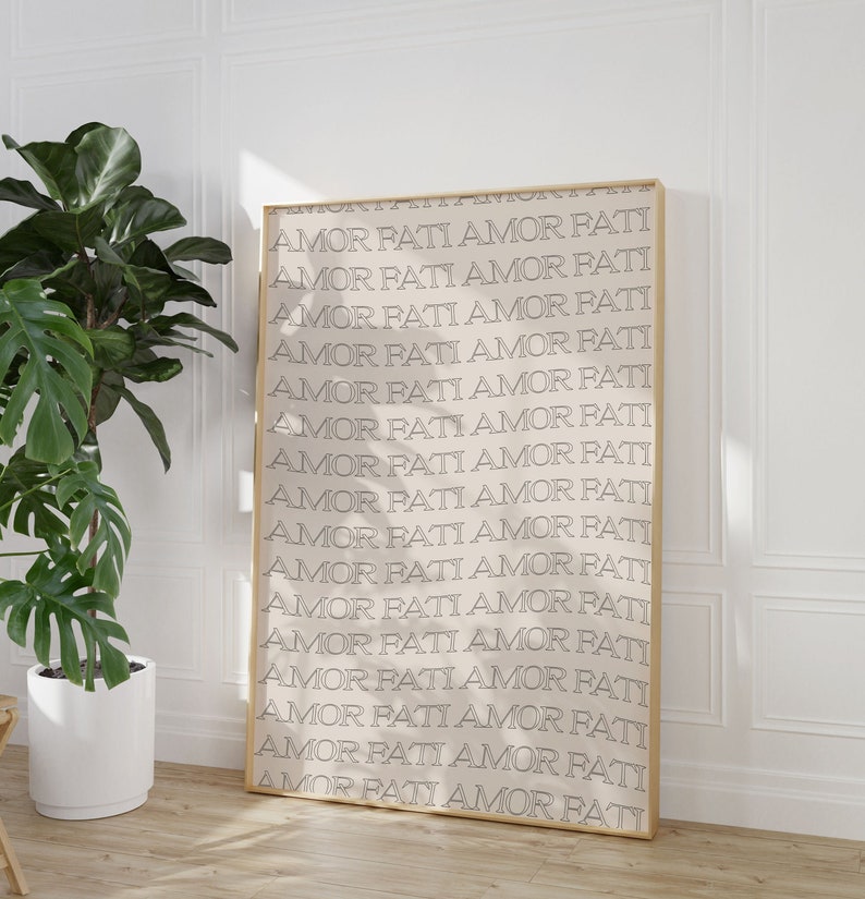 May include: A gold-framed print with the phrase "Amor Fati" repeated in a minimalist font on a cream background.