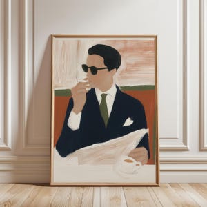 May include: Art print of a man in a dark suit and sunglasses, holding a cigarette and newspaper, with a cup of coffee. The artwork has a vintage aesthetic, with a color palette of navy, beige, and olive green. The print is framed in a light wood frame.
