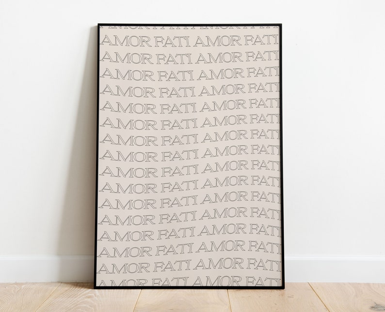 May include: A black framed print with the phrase "AMOR FATI" repeated in a white outline on a light beige background.