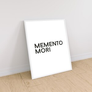 May include: A white framed print with the text "MEMENTO MORI" in black lettering.