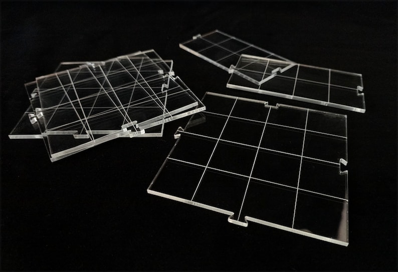 May include: Clear acrylic game board tiles with grid lines and interlocking edges. The tiles are arranged on a black surface, showcasing their transparent nature and geometric design. The tiles are designed for board games.