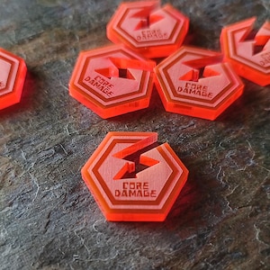 Puede incluir: Varios fichas de juego hexagonales de color naranja con las palabras "CORE DAMAGE" y un símbolo de rayo. Las fichas están hechas de un material translúcido y están dispersas sobre una superficie gris texturizada.