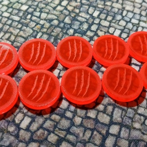 May include: Ten bright red plastic tokens with a claw mark design.