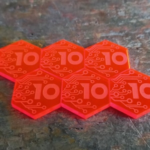May include: Six red hexagonal game pieces with a circuit board design and the number "10" printed on each piece.