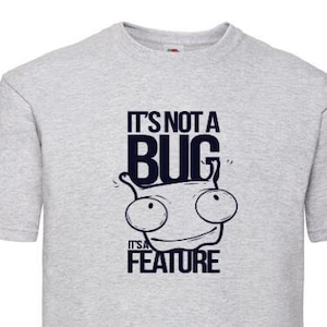 以下が含まれることがあります： グレーのTシャツに、漫画の虫と「バグではなく、機能です。」というテキストが書かれています