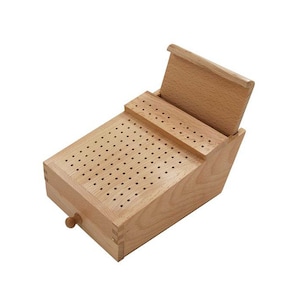 May include: A wooden box with a hinged lid and a small drawer. The box has a grid of holes on the top and is made of light brown wood.