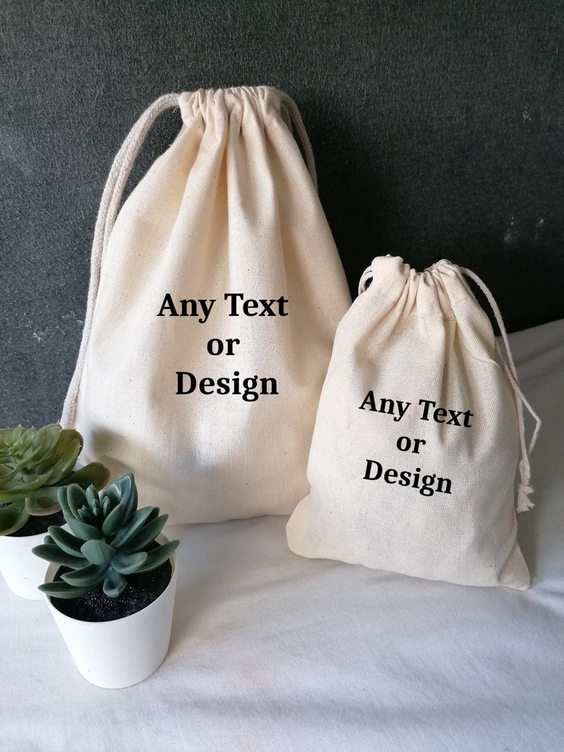 May include: Two white cotton drawstring bags with black text. The larger bag says "Any Text or Design". The smaller bag says "Any Text or Design".