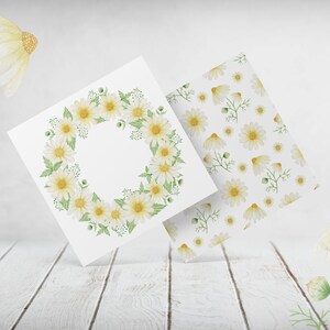 May include: Two white cards with watercolor illustrations of white daisies. One card features a wreath of daisies, the other card has a repeating pattern of daisies.