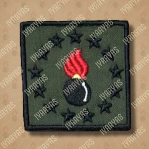 May include: Embroidered patch featuring a black bomb with a red flame and black stars on a green background. The patch has a black border and is square-shaped. The patch is likely for military or tactical apparel.