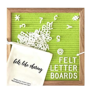May include: A green felt letter board with a wooden frame. The board is filled with white plastic letters, numbers, and symbols. A white drawstring bag with the text "felt like sharing" is in front of the board.