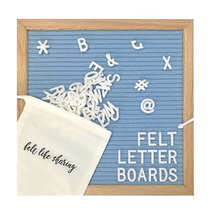 May include: A blue felt letter board with a wooden frame and white felt letters in a white drawstring bag. The bag has the text "felt like sharing" printed on it. The board has the text "FELT LETTER BOARDS" printed on it.