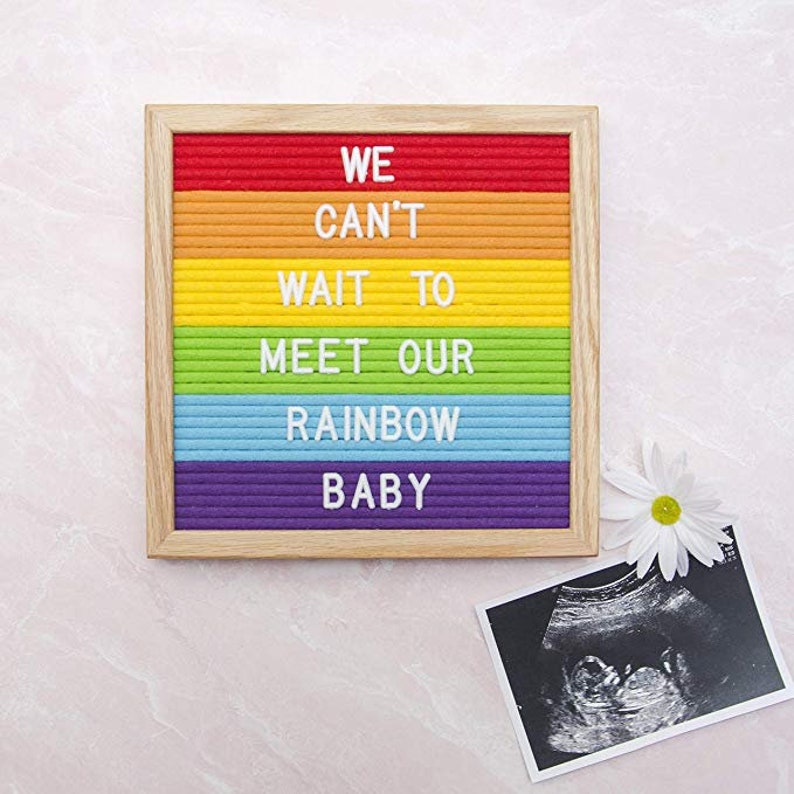 May include: A rainbow letter board with the message "WE CAN'T WAIT TO MEET OUR RAINBOW BABY". A black and white ultrasound image is below the board.