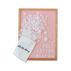 May include: A pink felt letter board with a wooden frame and white felt letters in a white drawstring bag. The bag has the text "felt like sharing" printed on it. The letter board has the text "FELT LETTER BOARDS" printed on it.