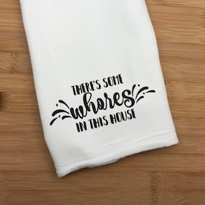 May include: White kitchen towel with black text that reads "There's some wheres in this house".