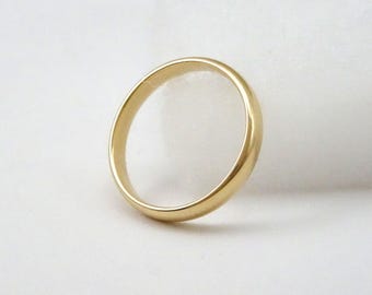 May include: A gold wedding band with a smooth, rounded design. The ring is made of polished gold and has a simple, classic style. The band is approximately 0.2 inches wide.