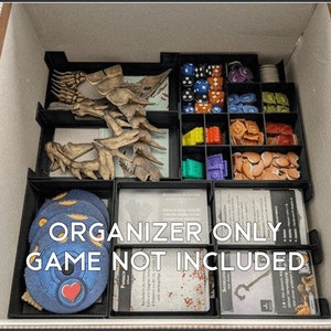 May include: A black organizer insert with compartments for storing game pieces. The insert is filled with various game components, including dice, tokens, and cards. The text "ORGANIZER ONLY!! GAME NOT INCLUDED" is printed on the front of the insert.
