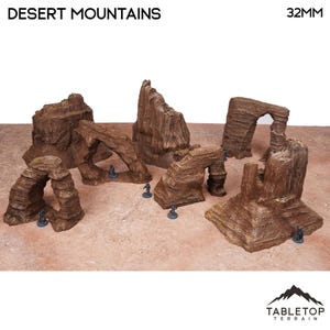 May include: A set of brown desert mountain terrain pieces for tabletop gaming. The set includes various rock formations, arches, and plateaus. The text "DESERT MOUNTAINS" and "32MM" are visible.