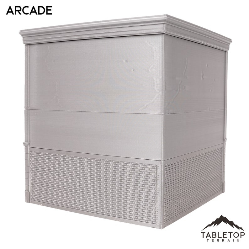 以下が含まれることがあります： グレーの3階建ての建物で、レンガ造りの土台と「ARCADE」と書かれた看板があります。