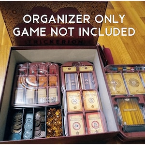 May include: A close-up of a brown wooden box with a clear plastic insert. The box is labelled "Organizer Only Game Not Included". The insert contains compartments for storing game pieces and cards. The box is filled with various game components, including coins, tokens, and cards.