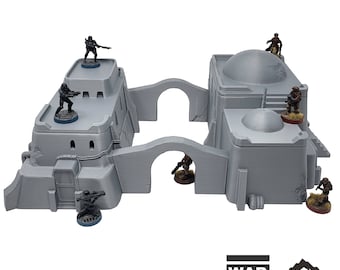 Op de afbeelding: Grijze Sandhouse 4 terreinmodel voor tabletop-oorlogsspellen. Het model heeft twee verbonden gebouwen met gewelfde loopbruggen en koepelvormige daken. Miniatuurfiguren zijn op de daken en loopbruggen geplaatst. De tekst "28-35mm" is zichtbaar.