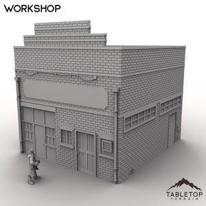 Puede incluir: Modelo de taller de ladrillo gris con la palabra "WORKSHOP" en la parte superior. El edificio tiene un letrero en blanco, varias ventanas y una puerta. Una pequeña figura está de pie frente al edificio. El logotipo de Tabletop Terrain está en la esquina inferior derecha.