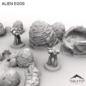 Könnte beinhalten: Ein Tabletop-Geländeset mit Alien-Eiern und zwei Miniatur-Soldaten. Die Eier sind groß, strukturiert und grau. Die Soldaten tragen futuristische Rüstungen und halten Waffen. Der Text "ALIEN EGGS" steht oben und "TABLETOP TERRAIN" unten.