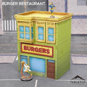 Puede incluir: Un edificio de dos pisos de color amarillo y verde con un letrero rojo que dice "BURGERS". El edificio tiene una puerta y ventanas marrones. Hay dos figuras de pie en el techo y frente al edificio.