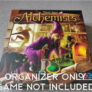 Puede incluir: Una caja para el juego de mesa "Alchemists" de Matúš Kotry. La caja presenta una ilustración de un mago con una túnica morada, un gato negro y una poción verde. El texto "ORGANIZER ONLY" y "GAME NOT INCLUDED" está impreso en la caja.