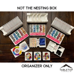 May include: White plastic organiser for the board game "Not the Nesting Box". The organiser includes compartments for cards, tokens, dice, and other game components. The organiser is labelled "Not the Nesting Box" and "Organiser Only".