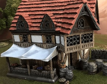 May include: A miniature model of a two-story building with a red tiled roof, a white awning, and a wooden facade. The building has a variety of windows and doors, and there are barrels and other details on the exterior. The model is painted in a realistic style and is suitable for use in tabletop games or dioramas.